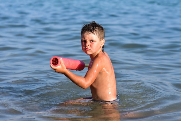 Garçon en colère dans un pistolet à eau en mer