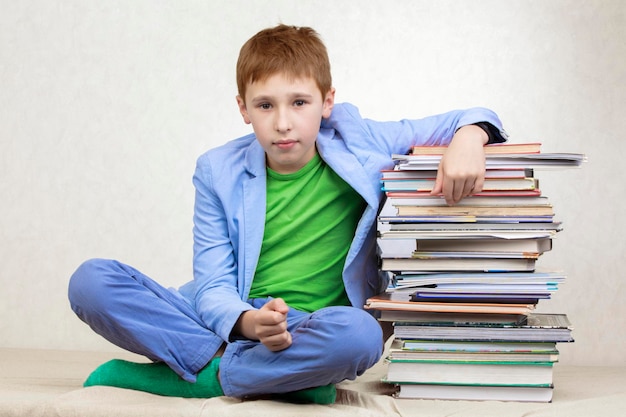 Un garçon de collège s'est penché sur une pile de livres