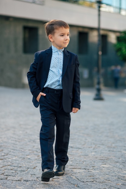 Garçon en costume d'affaires bleu foncé classique marche