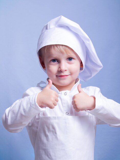 garçon en costume et une casquette de chef sourit