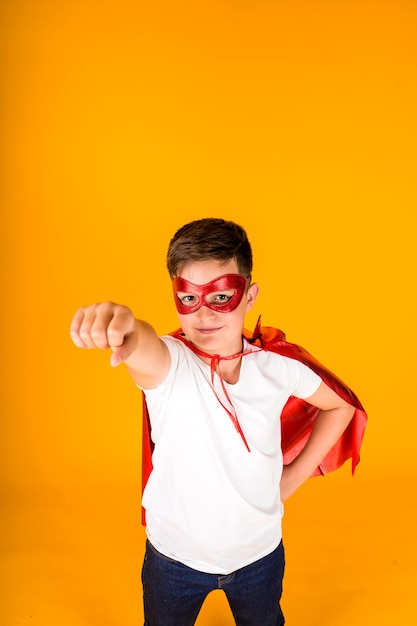 Un garçon en costume de héros se dépêche d'aider sur un fond jaune avec une place pour le texte