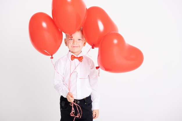 Garçon En Costume Et Nœud Papillon Rouge Détient Des Ballons Coeur