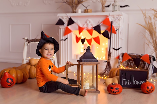 Photo garçon en costume de sorcière halloween avec citrouille