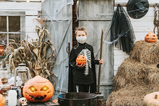Un garçon en costume de squelette portant un masque protecteur lors d'une fête d'Halloween dans une nouvelle réalité en raison de la pandémie de covid