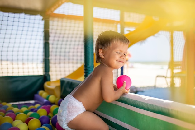 Garçon en couche avec ballon jouant dans la salle de jeux le week-end