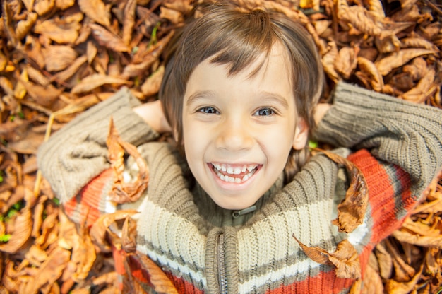 Garçon couché sur des feuilles sèches