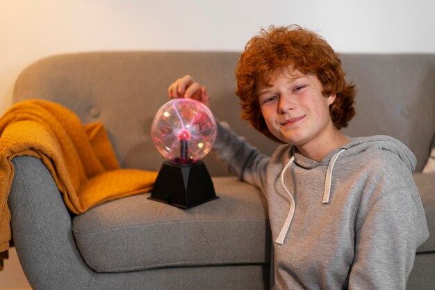 Photo garçon à coup moyen interagissant avec une boule de plasma