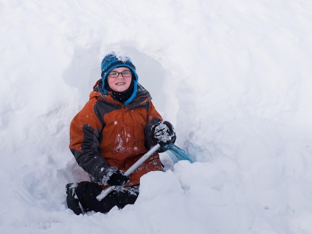 Un garçon creusant la grotte de neige.