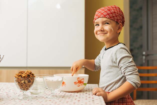 Garçon cuisine dans une cuisine lumineuse mélangeant des ingrédients tout en co