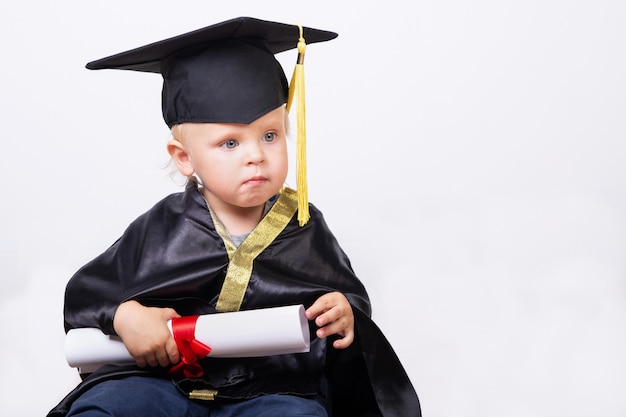 Photo garçon dans un baccalauréat ou un costume de maître avec défilement de diplôme isolé sur un fond clair avec copie espace. développement précoce, remise des diplômes, éducation, science, concept de bébé d'apprentissage précoce