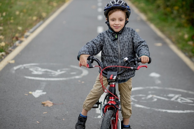 Garçon dans un casque à vélo sur une piste cyclable dans le parc