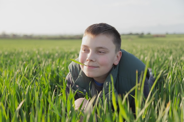 Un garçon dans un champ d'herbe avec un bâton dans la bouche