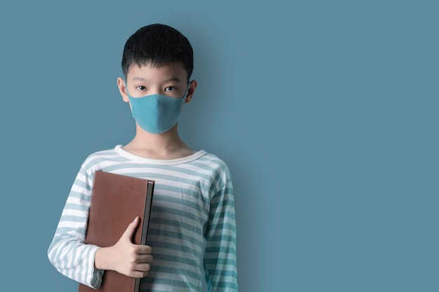 Garçon dans un masque médical de protection du visage sur fond bleu