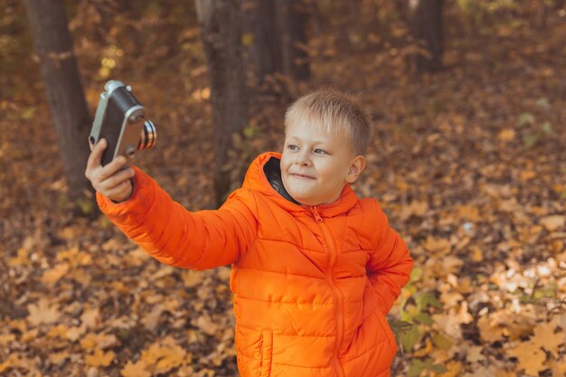 Garçon dans le parc en automne prenant une photo de selfie. Concept d'automne et de loisirs.