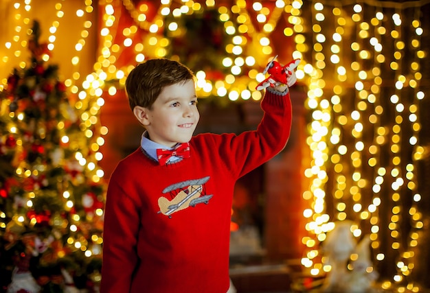 Garçon dans un pull rouge vif au milieu des lumières de Noël