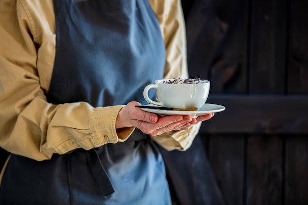 Garçon dans un tablier est titulaire d'un cappuccino