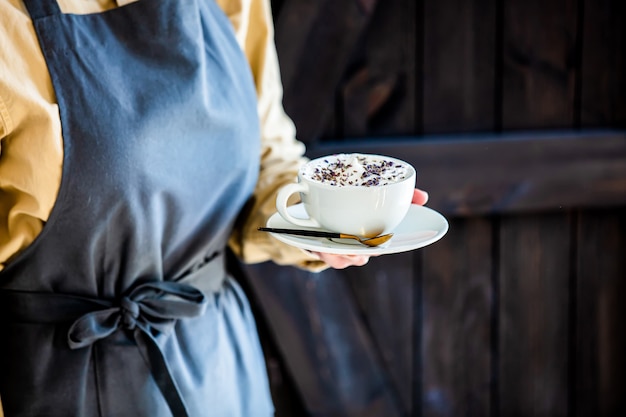 Garçon dans un tablier est titulaire d'un cappuccino