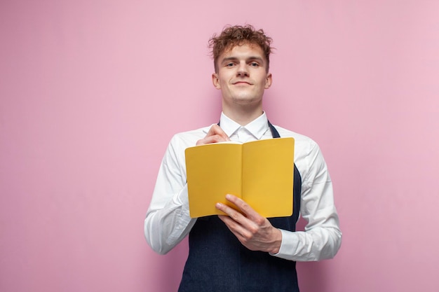 Un garçon dans un tablier prend une commande et écrit dans un cahier un employé de restaurant en uniforme