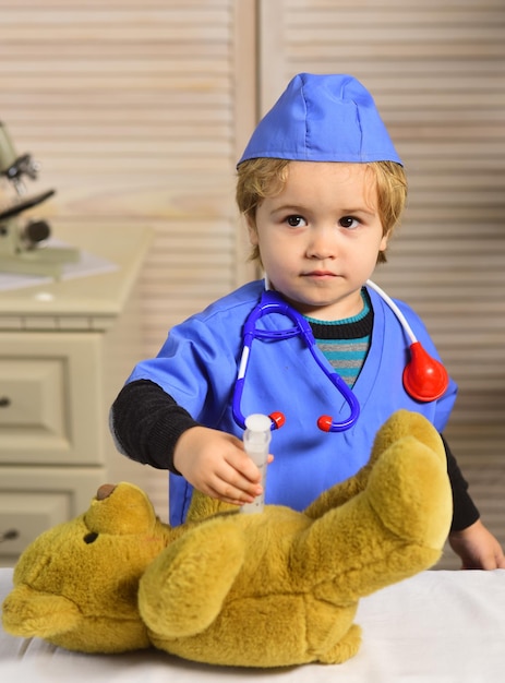 Photo le garçon dans l'uniforme chirurgical tient la seringue sur le fond en bois