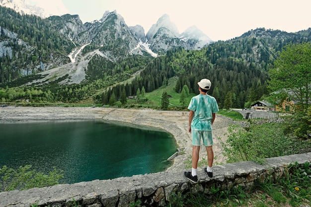 Garçon debout contre le lac et les montagnes à Vorderer Gosausee Gosau Haute-Autriche