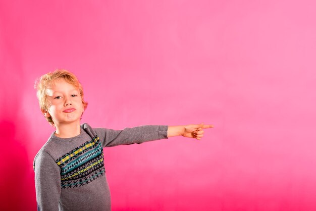 Photo un garçon debout sur un fond rose