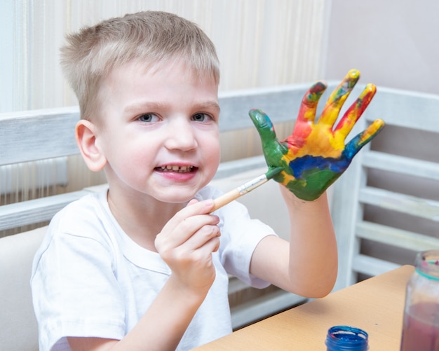 garçon décore ses mains avec des couleurs différentes