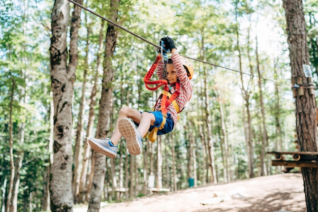 Le garçon descend la tyrolienne dans le parc aventure