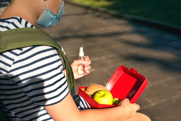 Garçon avec désinfectant pour les mains et boîte à lunch