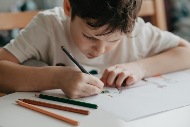 Le garçon dessine avec des crayons dans la cuisine en gros plan photo de haute qualité