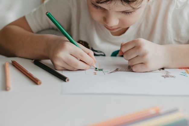 Le garçon dessine avec des crayons dans la cuisine en gros plan photo de haute qualité