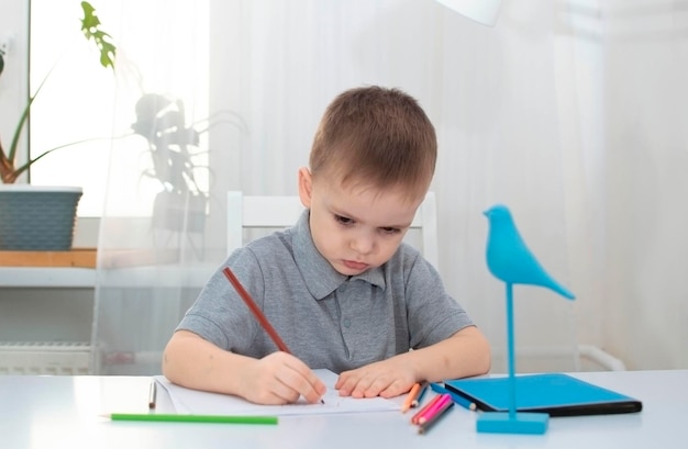 Le garçon dessine dans sa chambre à son bureau L'enfant est engagé dans la créativité à la maison Le concept de la créativité des enfants Mise au point sélective