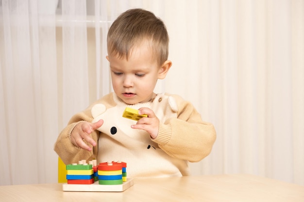 Un garçon de deux ans joue avec des jouets en bois pour développer sa logique et sa motricité.