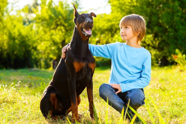 Photo garçon avec dobermann dans le parc d'été.