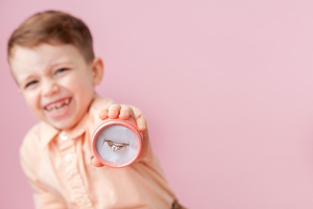 Garçon donnant une bague en boîte sur fond rose