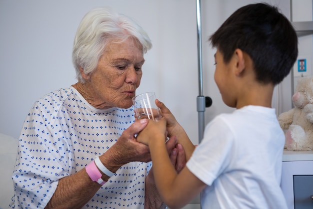 Garçon donnant un verre d'eau au patient senior