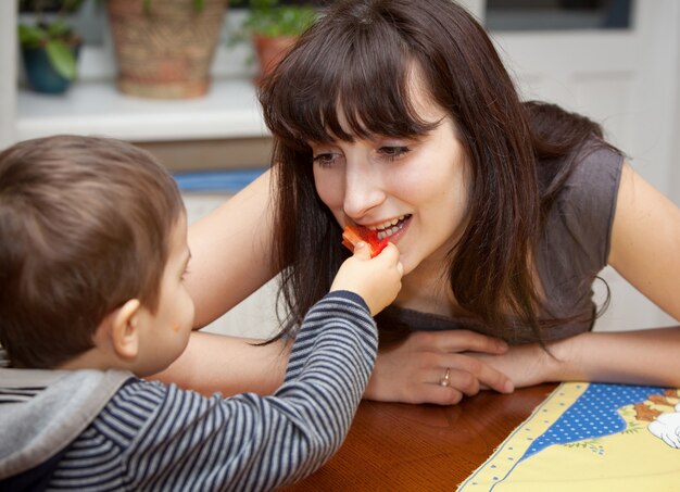 Un garçon donne un morceau de poivron rouge à sa mère