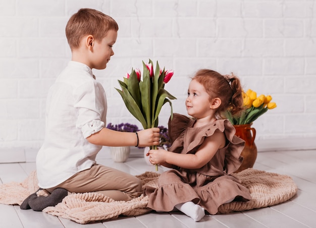 Un garçon donne à une petite fille un bouquet de tulipes. Fleurs pour les vacances