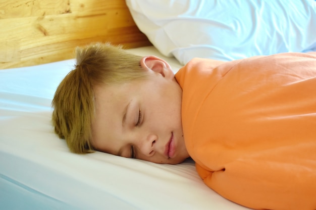 le garçon dort doucement sur le lit à la maison