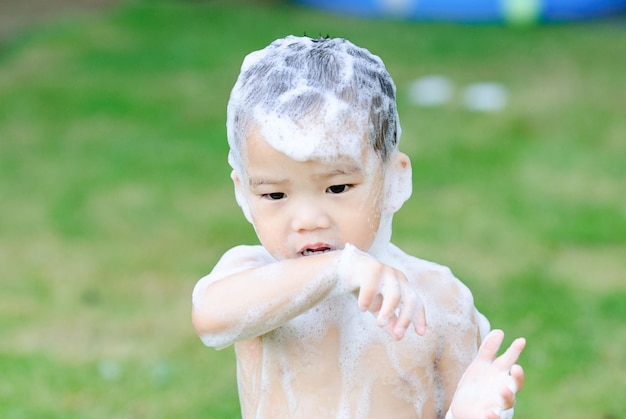 Garçon de douche dans le jardin avec de la mousse.