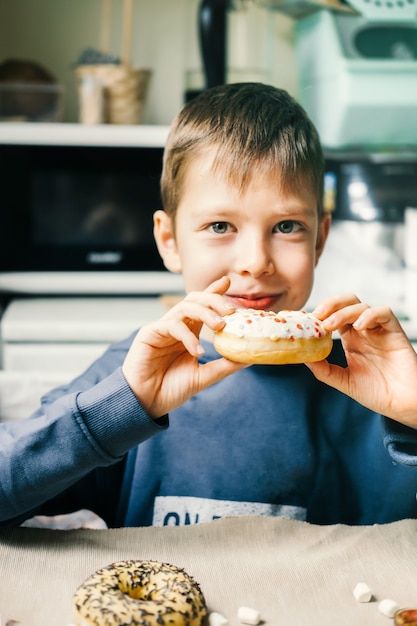 Garçon drôle avec beignet. l'enfant s'amuse avec le beignet. Nourriture savoureuse pour les enfants. Bon moment à la maison avec des aliments sucrés.