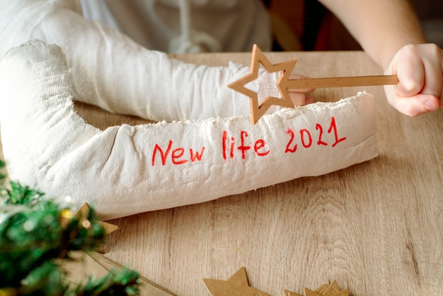 Garçon avec du plâtre moulé sur son bras fait de l'artisanat de Noël. Fracture de la main et blessure. Enlève le plâtre en attendant une nouvelle vie. Nouvelle année et nouveaux plans.