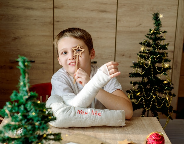 Garçon avec du plâtre moulé sur son bras fait de l'artisanat de Noël. Fracture de la main et blessure. Enlève le plâtre