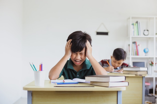 Garçon de l'école primaire fatigué et stressé en faisant des examens en classe