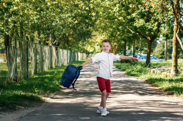 Un garçon d'une école primaire avec un sac à dos dans la rue