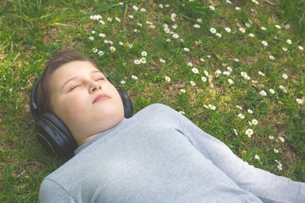 Garçon écoutant ou profitant d'une musique à l'extérieur ou dans un parc avec d'énormes écouteurs