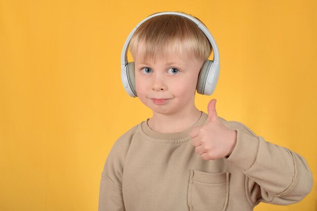 Un garçon avec des écouteurs donnant un coup de pouce sur un fond jaune