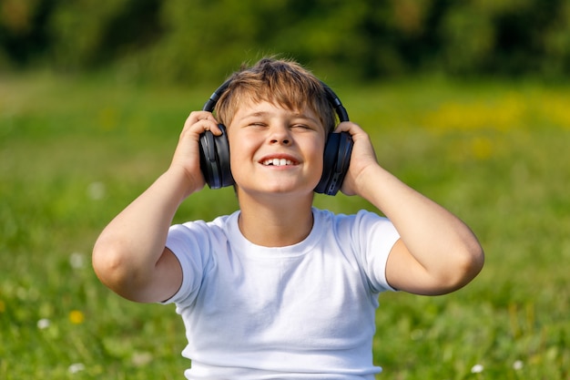 Garçon avec des écouteurs, écouter de la musique assis sur l'herbe