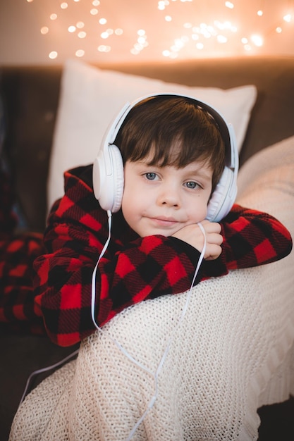 Un garçon avec des écouteurs est allongé sur le mode de vie du canapé Le garçon écoute de la musique