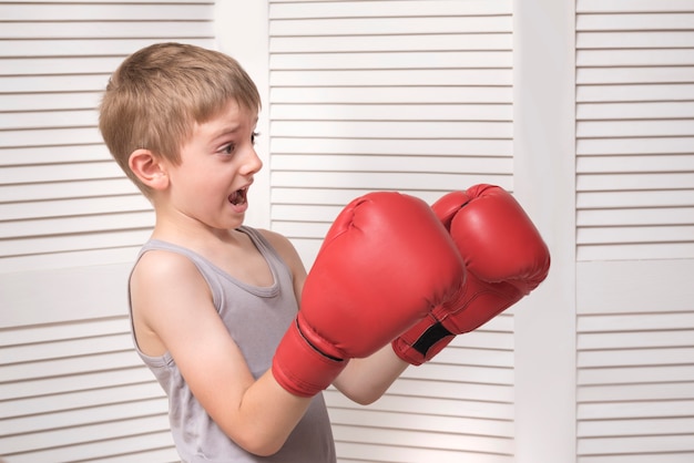 Garçon effrayé dans des gants de boxe rouges.