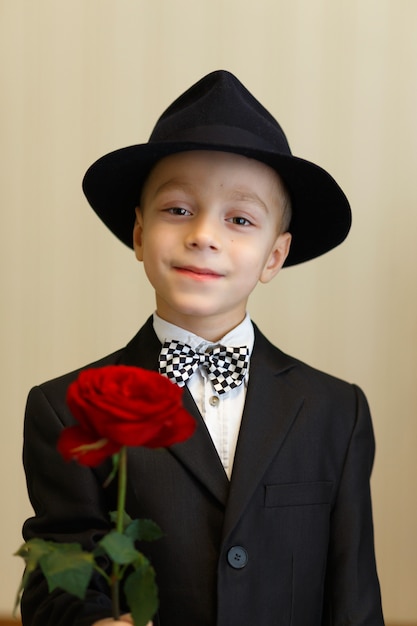 Garçon élégant en costume et bonnet avec une rose